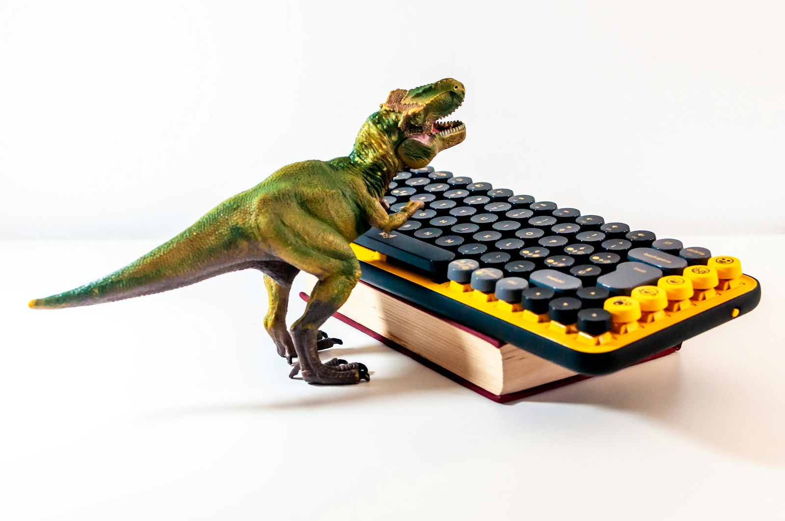 A toy dinosaur is playing with a computer keyboard
